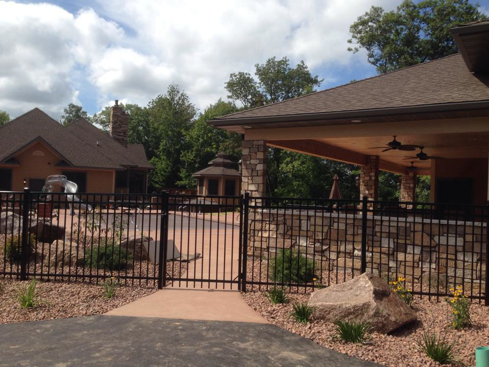 A sturdy black metal fence and gate enclosing an outdoor living area, built by Ankeny Builders L.L.C. in Eau Claire, WI.