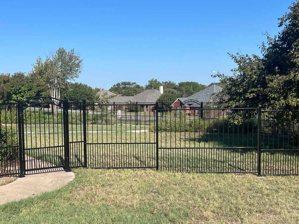 A stylish black metal fence and matching gate installed by Tin Star Fencing in Fort Worth, TX