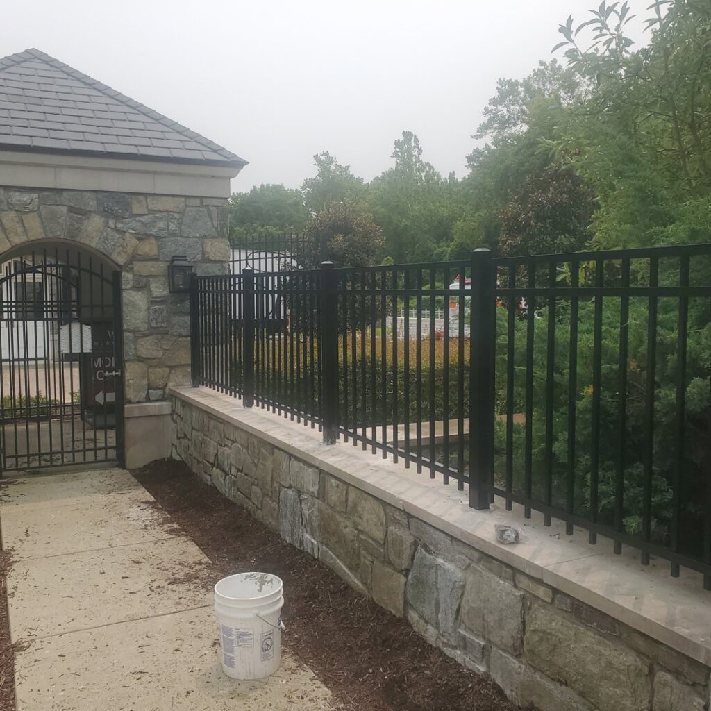 A black metal fence installed on a stone wall by Quality Fence & Deck Co. in Frederick, MD.