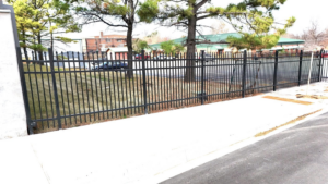 A durable black metal security fence installed along a sidewalk at a commercial site by Aaron Fence in Tulsa, OK.