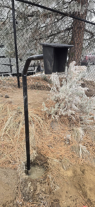 Installation of a black metal gate or access control post set in concrete by Michel's Fencing in Bend, OR