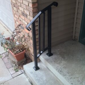 Newly installed black metal handrail on concrete steps, a service provided by SAM'S Handywork LLC in Independence, IA.