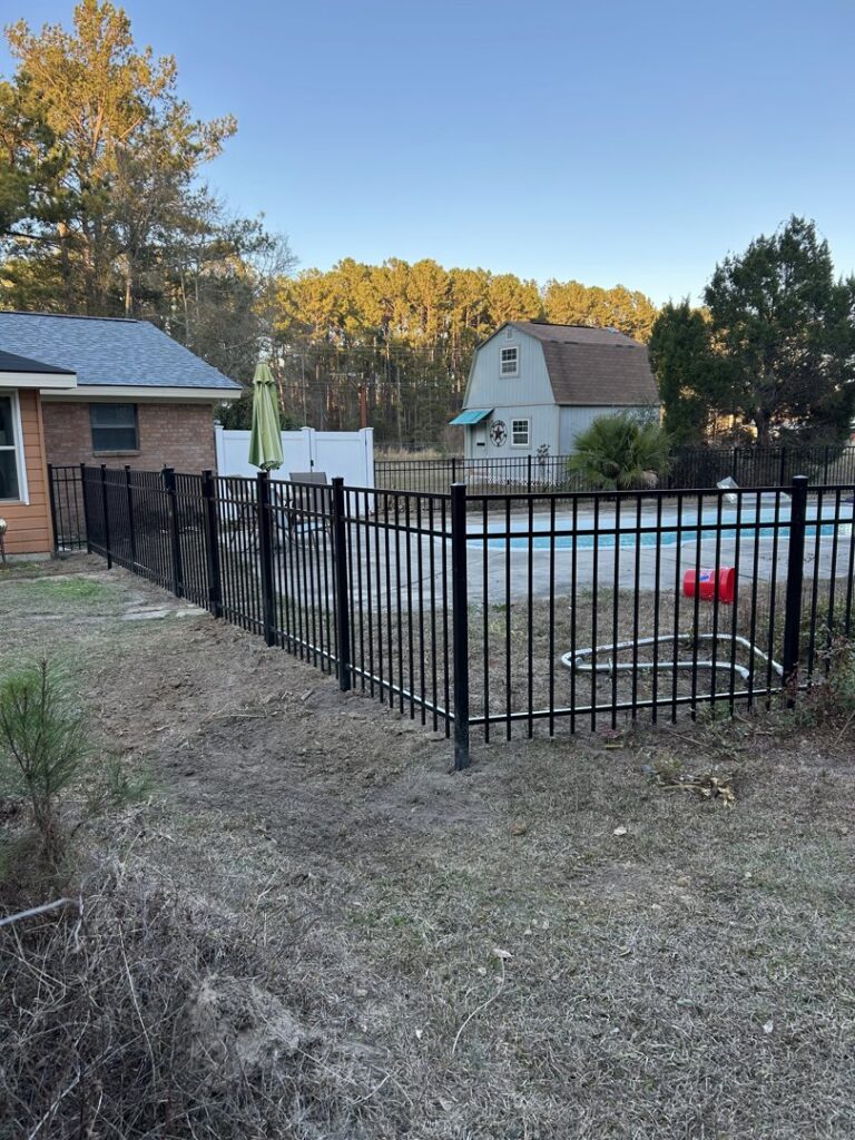 A newly installed black metal fence surrounding a pool area by Fence & Deck Connection, Inc. in Savannah, GA.