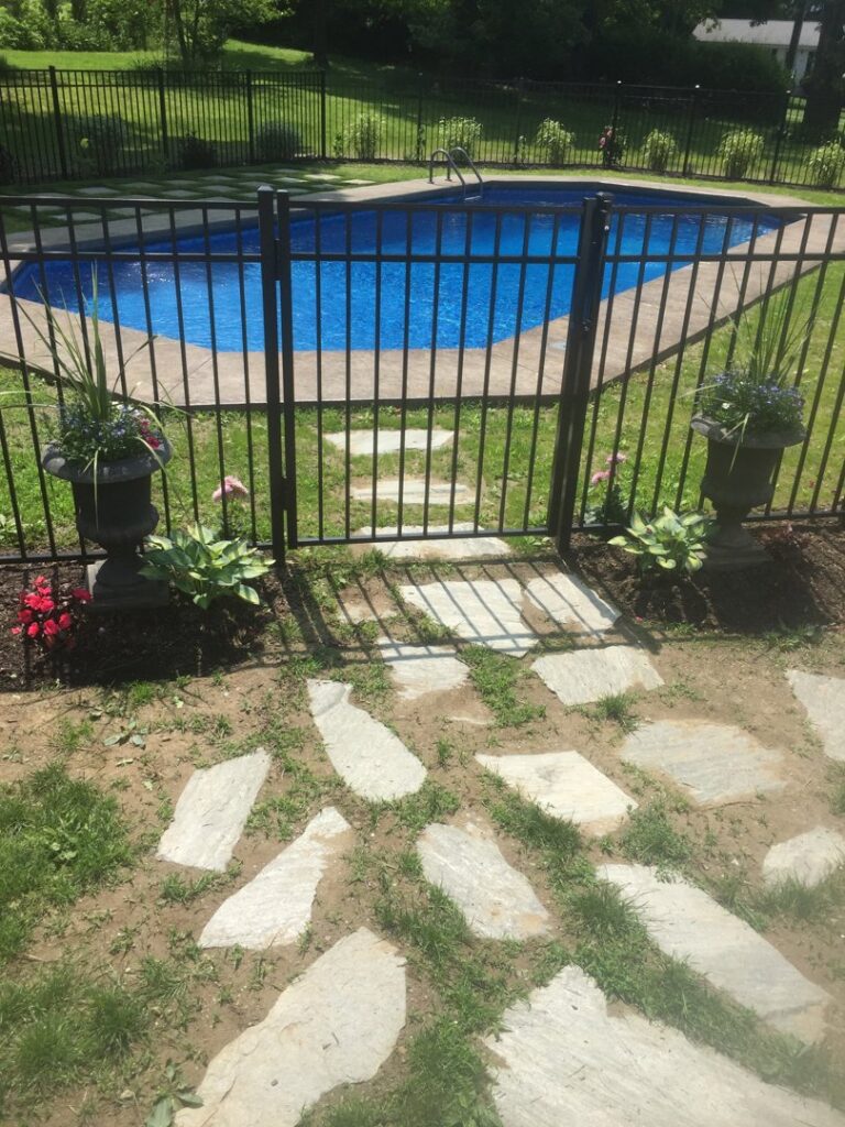 A newly installed black metal fence and gate providing safety around a pool by Hat City Pools in Danbury, CT