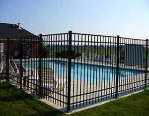 A black metal safety fence installed around a swimming pool by R & C Fence in Fort Wayne, IN.