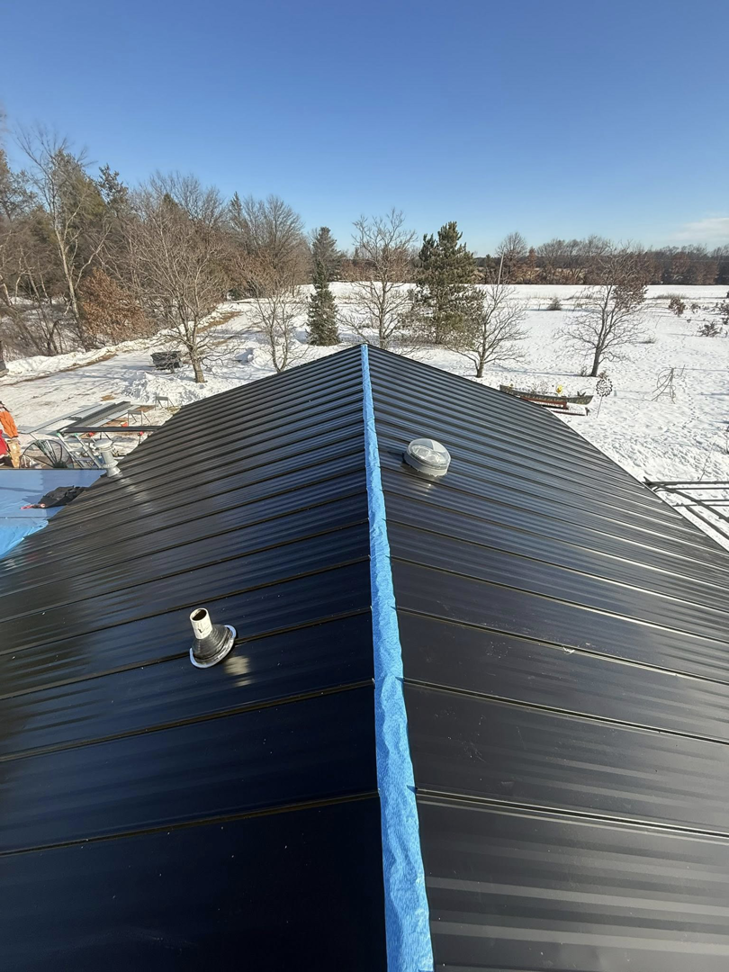 A black metal roof installation in progress on a house by Timeless Exteriors Inc in Fort Wayne, IN