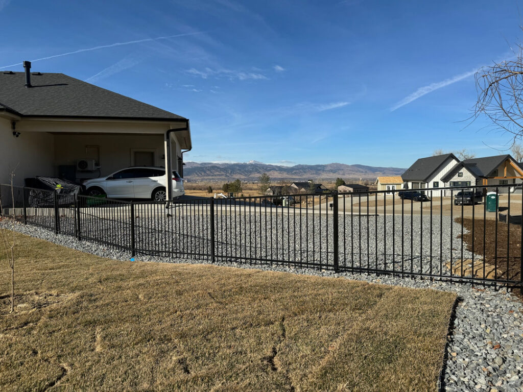 A black metal security fence installed by GreenView Solutions in Denver, CO, with mountain views.