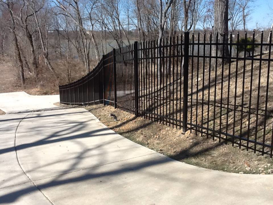 A durable black metal security fence installed along a curved path by Fence Me In And Decks Too in Glen Allen, VA.