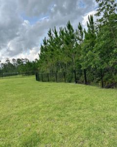 A durable black metal security fence installed around a large grassy field by LV Fence and Gates in Jacksonville, FL.