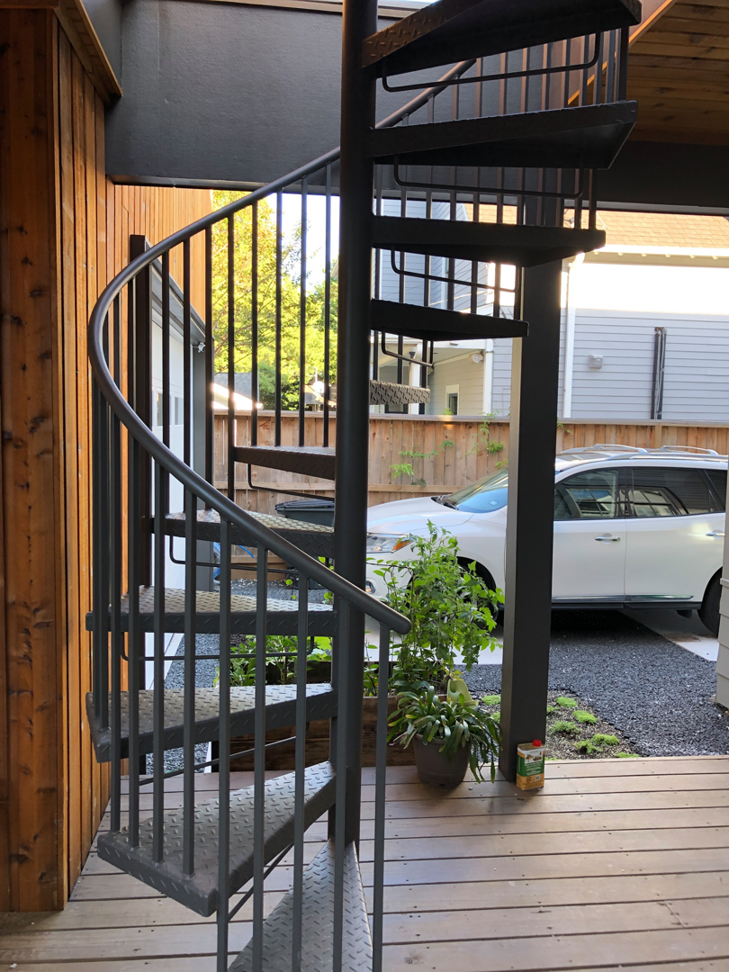 A black metal spiral staircase providing access to an outdoor deck, built by Kaleidoscope Design Build in Houston, TX.