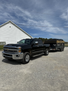 A black pickup truck towing a loaded dump trailer, ready for disposal by Salt Creek Disposal in Bowling Green, KY.