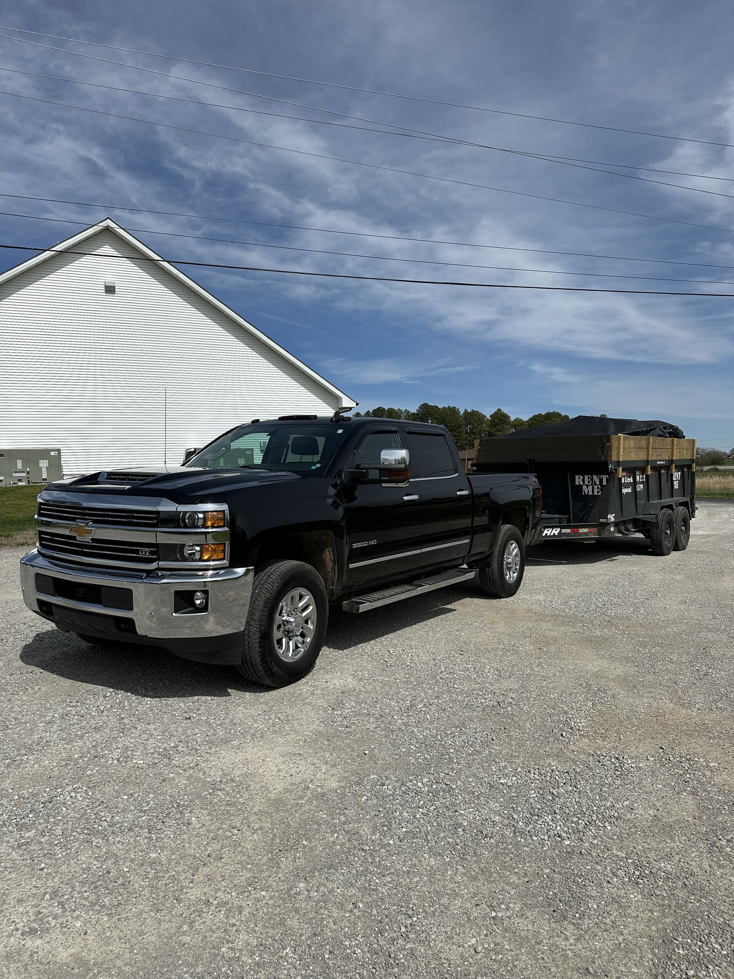 A black pickup truck towing a loaded dump trailer, ready for disposal by Salt Creek Disposal in Bowling Green, KY.