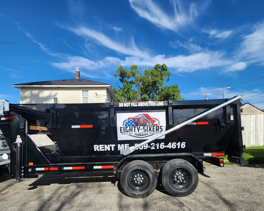A black roll-off dumpster trailer with the Eighty-Sixers Roll Off Dumpster Services logo and contact information in Spokane, WA.