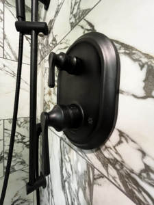 A modern black shower fixture expertly installed on elegant marble-look tiles by Simko Tile & Bath in Macon, GA.