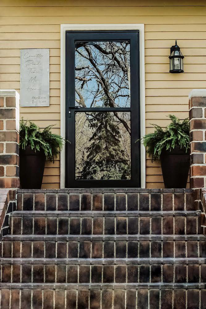 A newly installed black storm door on a yellow house by Denver Storm Door in Denver, CO.