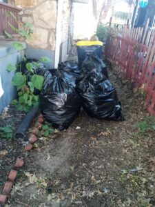 Several black trash bags neatly stacked by the side of a house, indicating a cleanout and junk removal service by Little Tykes Property Preservation in Independence, MO.