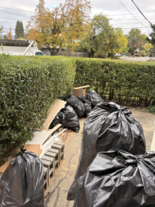 Multiple black trash bags filled with debris and wood scraps ready for hauling by HB Junk Hauling LLC in Springfield, OR.