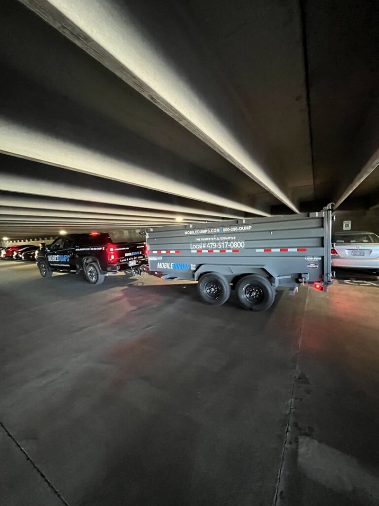 A black pickup truck towing an empty Mobiledumps trailer for junk removal services in Rogers, AR.