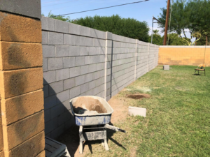 Block wall construction in progress with a wheelbarrow of materials by Ken's Masonry, LLC in Chandler, AZ.