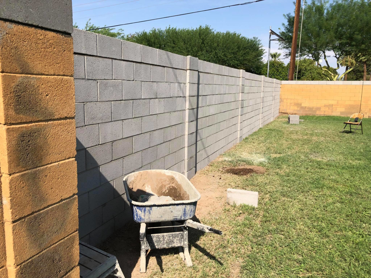 Block wall construction in progress with a wheelbarrow of materials by Ken's Masonry, LLC in Chandler, AZ.