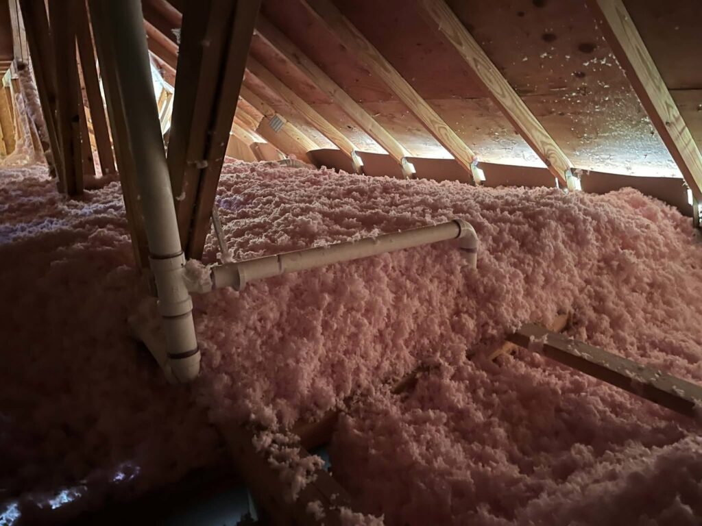 Blown-in pink insulation covering an attic floor installed by ADDICT INSULATION, LLC in St. Charles, MO.