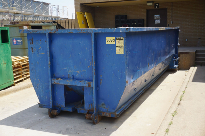A blue 30-yard dumpster parked outside a commercial building, available for rent from Massie Dumpster Rental in Las Vegas, NV.
