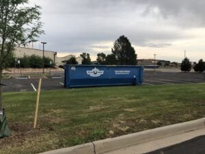 A Blue Bear Waste Services dumpster placed in a large parking lot for commercial waste in Denver, CO.
