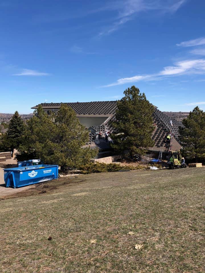 A Blue Bear Waste Services dumpster on site for a residential roofing job in Denver, CO.