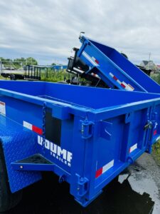 A bright blue dump trailer, ideal for hauling materials, available from Handyman Vehicle Outfitters in Portland, ME.
