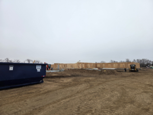 A blue dumpster at a construction site, provided by Miedema Sanitation Inc of Huron SD in Mitchell, SD.