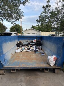 A blue roll-off dumpster partially filled with office junk, ready for removal by Evergreen Disposal in Kalispell, MT.