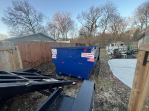 A blue dumpster placed in a residential backyard by Great Lakes Bins in South Bend, IN, ready for junk removal.