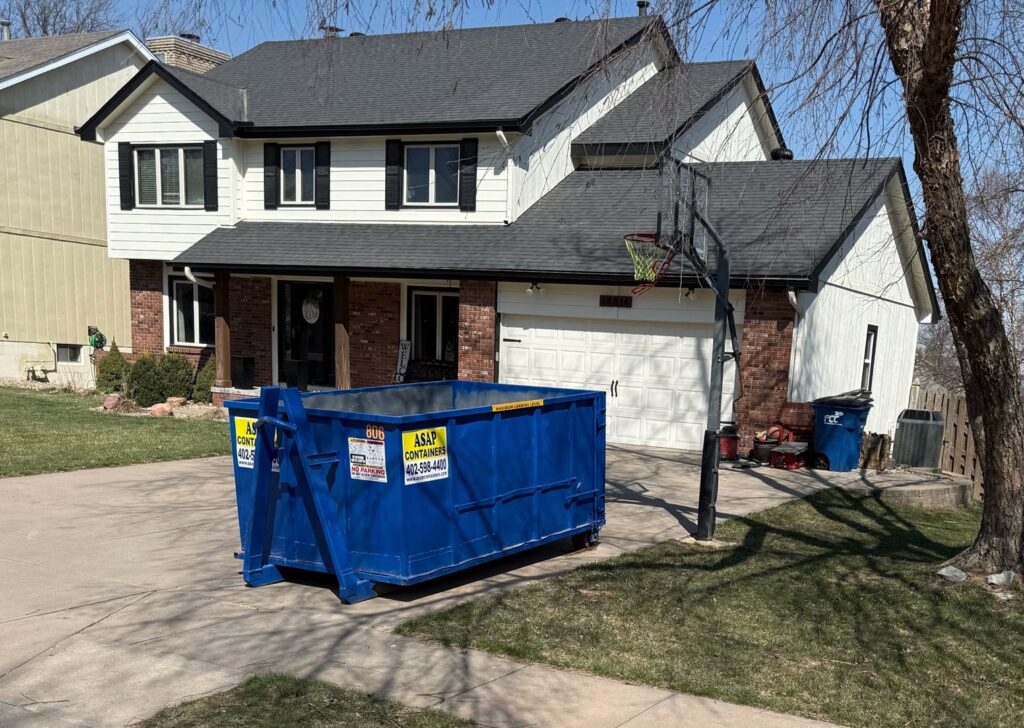 An ASAP Containers inc. blue dumpster in a residential driveway for junk removal services in Omaha, NE.