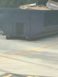 A blue roll-off dumpster partially filled with cardboard boxes, used for junk removal by Waste Master Dumpster Rental Orlando, FL.