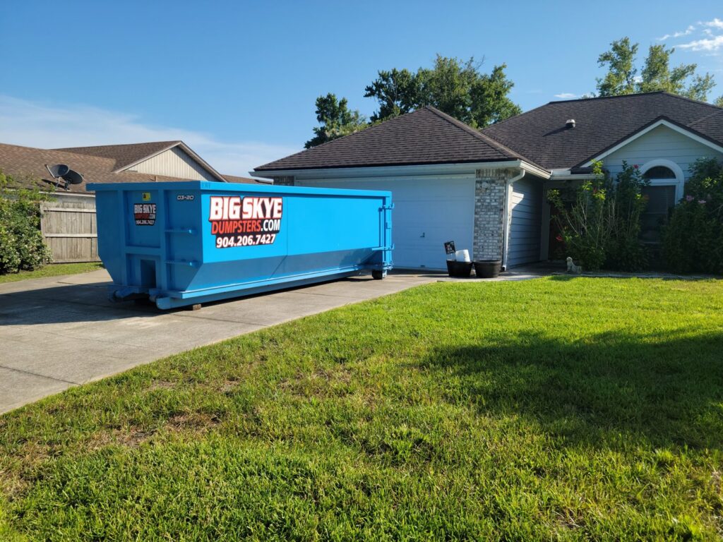 A blue dumpster from Big Skye Dumpsters placed in a residential driveway in Jacksonville, FL.