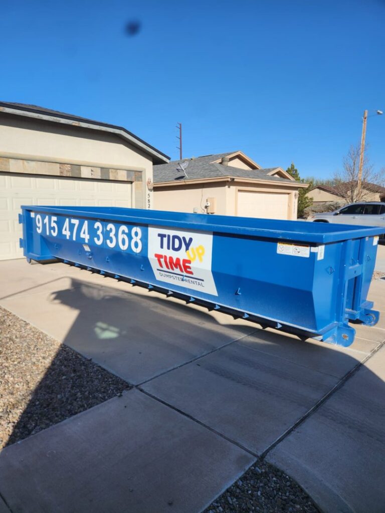 A blue Tidy up time dumpster placed in a residential driveway for junk removal services in El Paso, TX.
