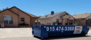 A blue Tidy up time dumpster parked on a residential street, ready for junk removal in El Paso, TX.