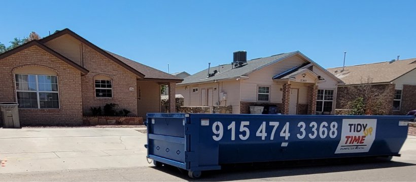 A blue Tidy up time dumpster parked on a residential street, ready for junk removal in El Paso, TX.