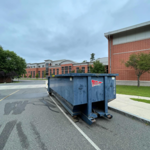 A blue roll-off dumpster from Chet's Disposal placed in front of a school building in Springfield, MA.