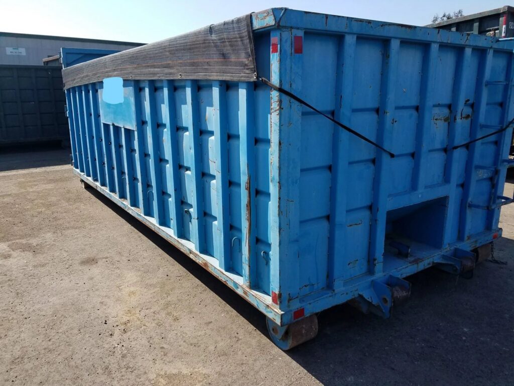 A blue dumpster with a protective tarp covering debris, indicating a completed junk removal job by Massie Dumpster Rental in Las Vegas, NV.
