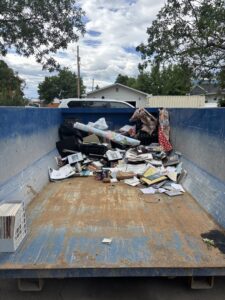 A blue roll-off dumpster partially filled with office waste and papers for removal by Evergreen Disposal in Kalispell, MT.