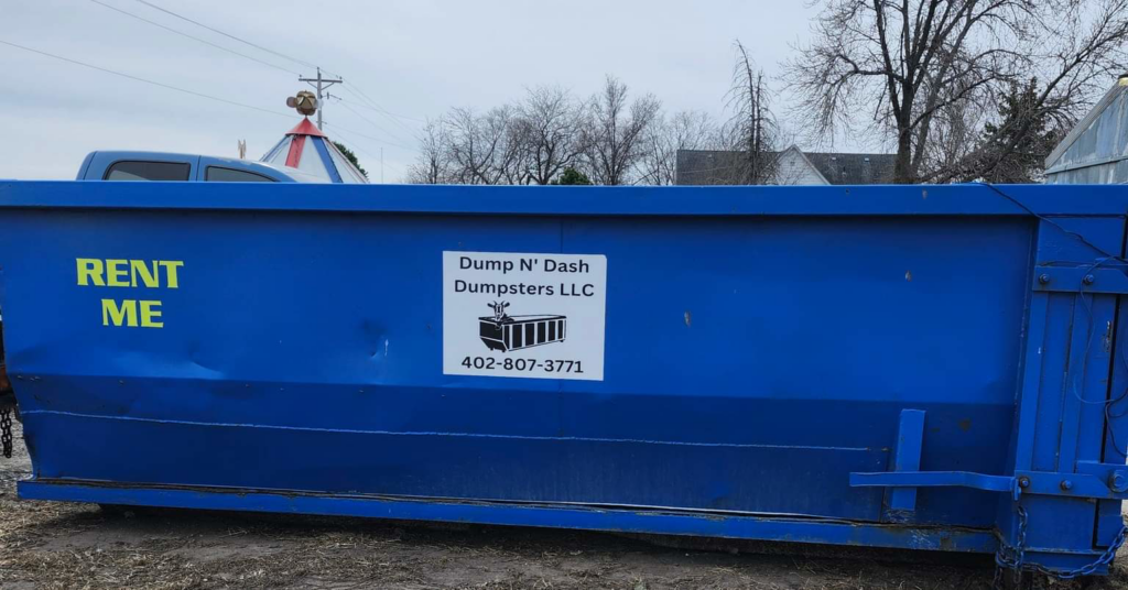 A large blue dumpster with a "RENT ME" sign from Dump N Dash Dumpsters LLC, ready for junk removal in Valley, NE.