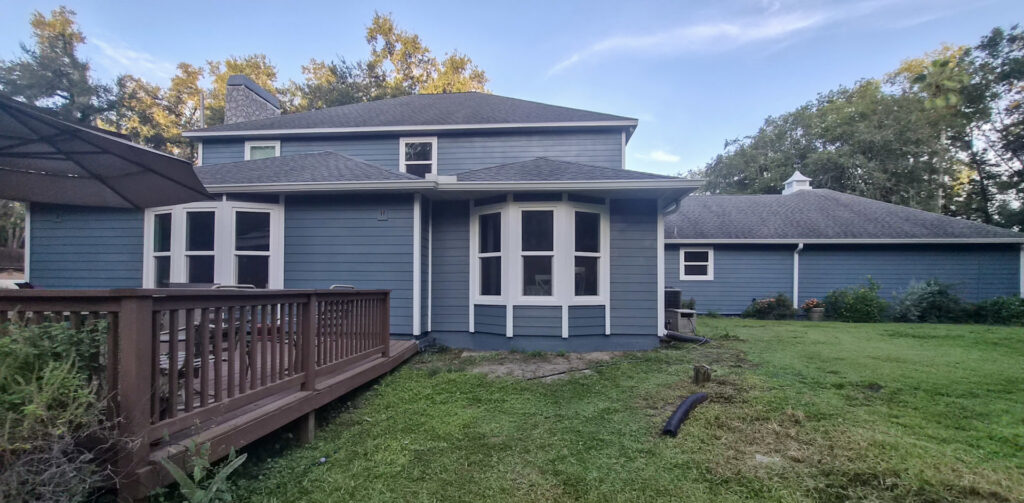A blue house with a wooden deck and multiple bay windows, showcasing exterior work by Alejandro Melo Contractor corp in Tampa, FL.