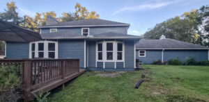 A blue house with a wooden deck and multiple bay windows, showcasing exterior work by Alejandro Melo Contractor corp in Tampa, FL.