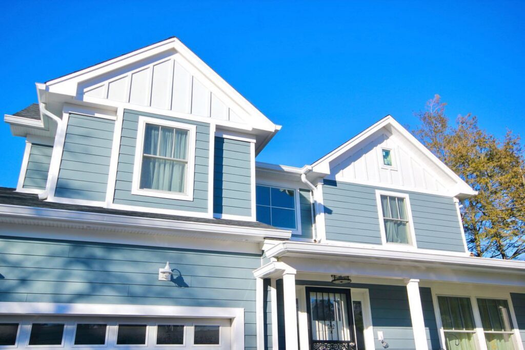 A beautiful blue house with crisp white trim and gables, showcasing a completed siding project by Ideal Siding Richmond, VA.