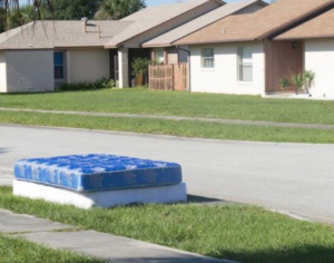 A blue mattress and box spring left on the grass for removal by Omaha junk Removal and Hauling Service in Omaha, NE.