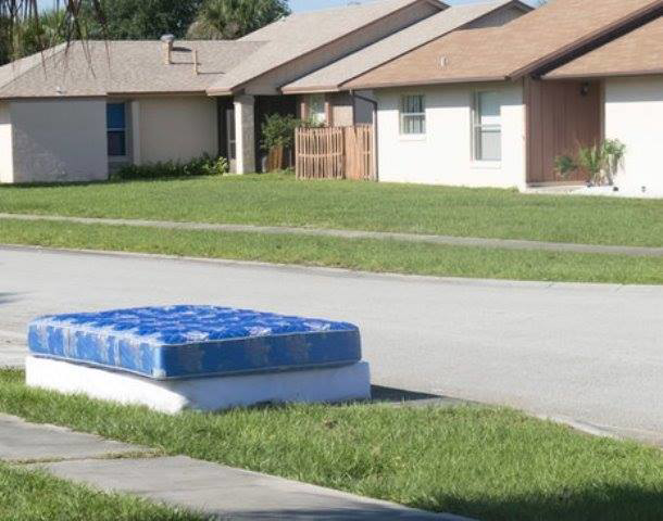 A blue mattress and box spring left on the grass for removal by Omaha junk Removal and Hauling Service in Omaha, NE.