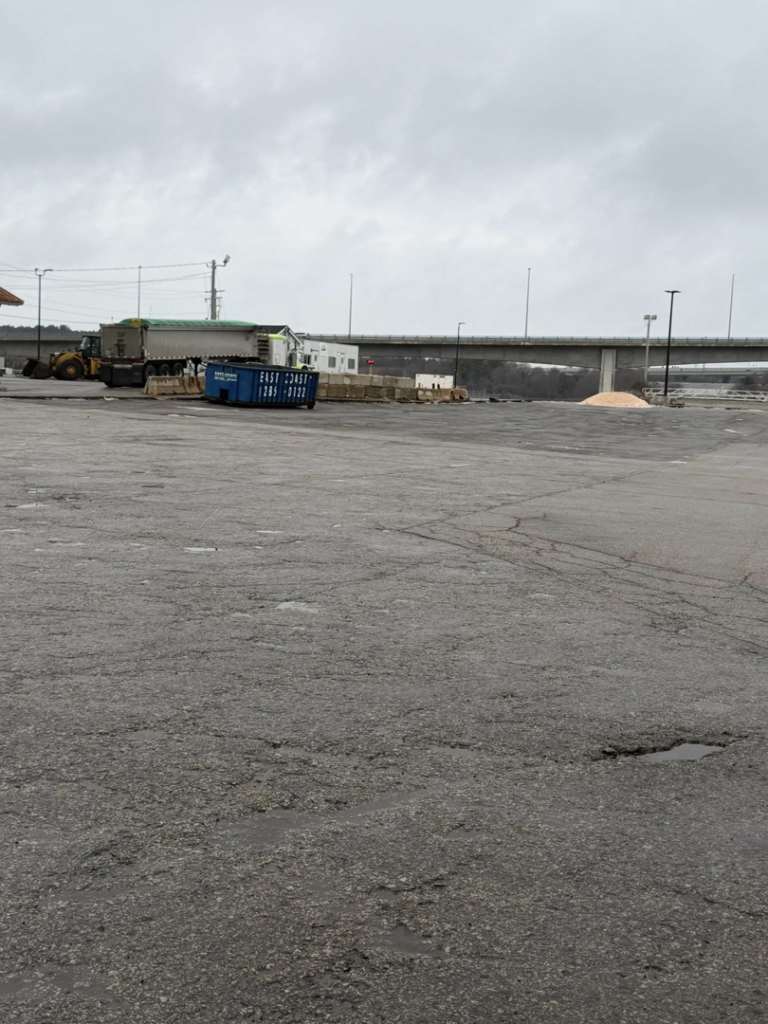 A blue roll-off container on a large paved job site provided by East Coast Container Services LLC in Northwood, NH.