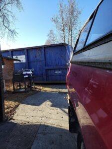 A large blue roll-off dumpster with the Alaska Waste logo, used for junk removal and waste management in Anchorage, AK.