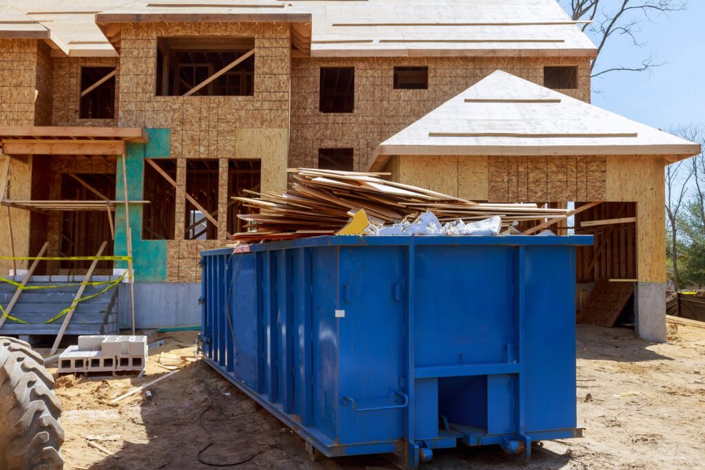 A blue roll-off dumpster filled with construction debris at a job site for junk removal by RBS Sanitation Inc. in Tea, SD.